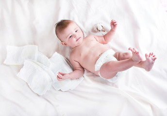 Baby in diaper on a white background with a branch of cotton