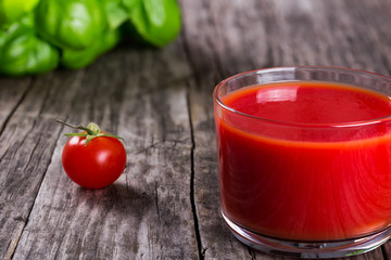 fresh tomato juice in a glass on an old wooden table, close up