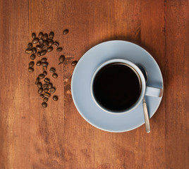 Cup of black coffee with coffee beans scattered around