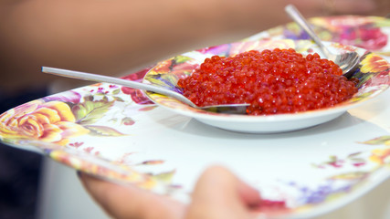 Raw salted red fish caviar on a plate. Slavic holiday tradition of meeting our dear guests. Fresh red salmon caviar.  The fish delicacy for gourmets.