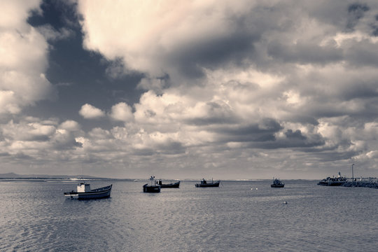 Traditional fishing boats in harbour with the ocean and clouds i
