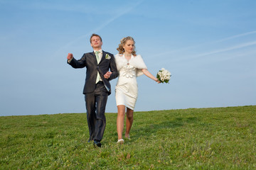 Newly wedded walking along the field