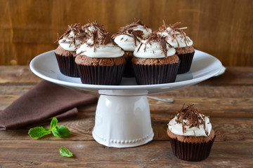 Chocolate cupcakes with cream and chocolate on a wooden backgrou