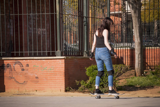 Beautiful young woman practicing with the skateboard on the stre