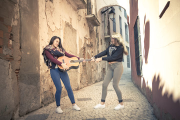 Momentos de inspiración. Momentos divertidos. Chicas paseando con una guitarra por la calle. Joven...