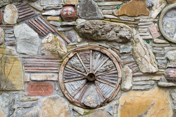 Fototapeta na wymiar Background. A stone wall with a wooden wheel and a jug