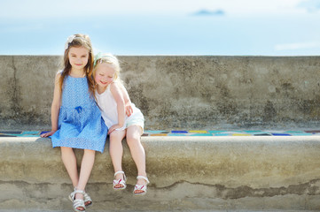 Two adorable little sisters laughing and hugging each other on warm and sunny summer day © MNStudio