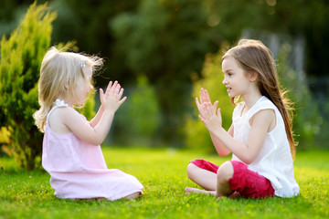 Fototapeta premium Two cute little sisters having fun together on the grass