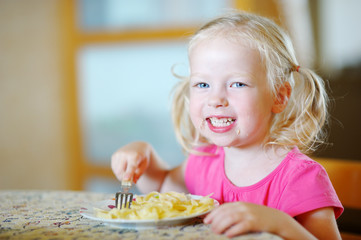 Cute funny little girl eating spaghetti