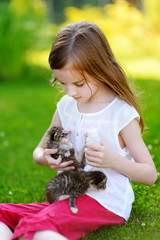 Adorable little girl playing with small kittens