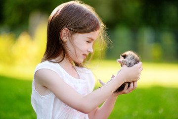 Adorable little girl playing with small kitten