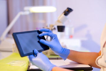 Female scientist using digital tablet in lab, close up. Selective focus