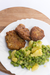 Homemade burgers served with potatoes and green peas