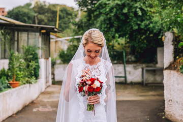 Fototapeta premium beautiful bride with bouquet from behind near flower bush