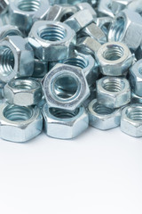 Macro image of pile of grey metal nuts over white background