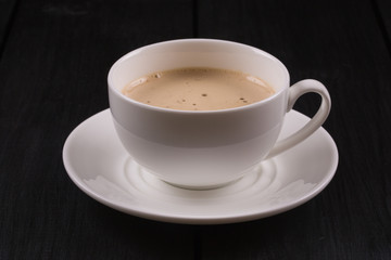 Cappuccino with cinnamon in a white cup. Coffee on Black Wooden Table
