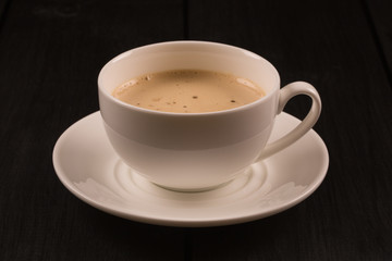 Cappuccino with cinnamon in a white cup. Coffee on Black Wooden Table