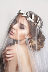 Naklejka premium Beautiful bride with fashion wedding hairstyle - on white background.Closeup portrait of young gorgeous bride. Wedding. Studio shot.Beautiful bride portrait with veil over her face
