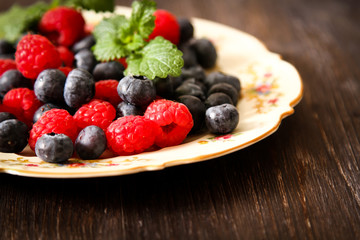 blueberries and raspberries on a plate ventazhnoy dark wood back