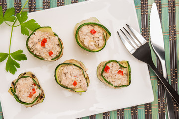 Grilled zucchini rolls with curd cheese and tuna on plate.