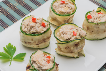 Grilled zucchini rolls with curd cheese and tuna on plate.