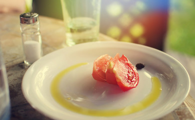 Summer breakfast with piece of tomato, olive oil on a plate 