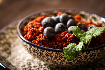 Quinoa blueberries and raspberries on a plate with black backgro