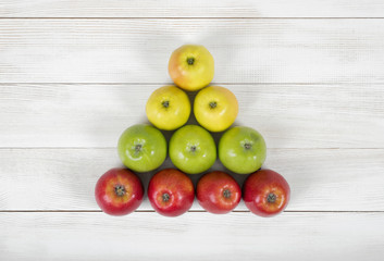 Top view of yellow, green and red apples creating a triangle shape