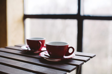 Two red cups on wooden plank table