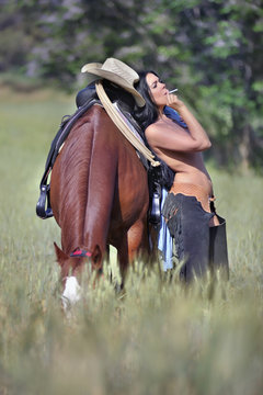 Portrait of smaking topless cowgirl near the horse