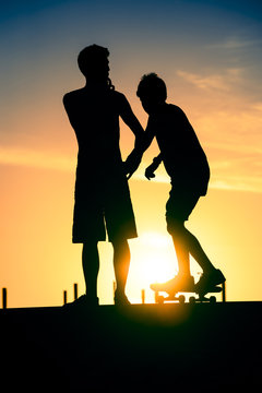 Friends silhouette at skate park on summer day