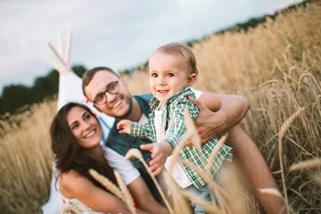 Young hipster father, mother cute baby son on picnic