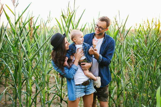 Young hipster family with cute baby in cornfield smiling