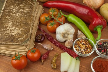 Old cookbook recipes on a wooden table. Cook healthy vegetable. Preparation of home diet food. Different kinds of vegetables.
