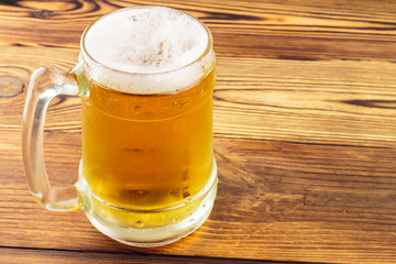 Mug of cold beer on wooden table
