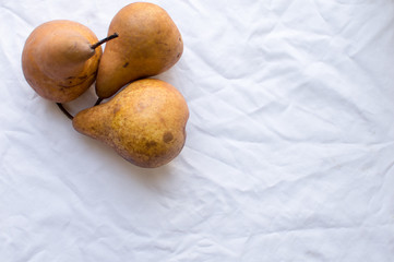 High angle view of three beurre bosc pears on a white tablecloth