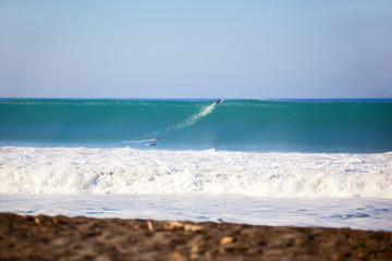 Surfers paddling over a big wave