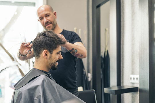 Hairstylist making men's haircut to an attractive man.