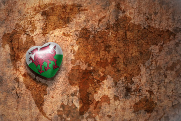Fototapeta premium heart with national flag of wales on a vintage world map crack paper background