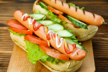 Spicy hotdog with fresh vegetables lying on wooden kitchen board