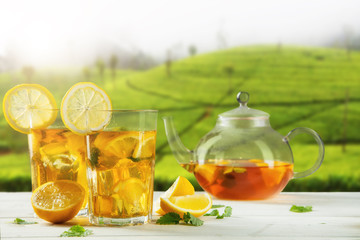 Cups of ice tea with plantation on background