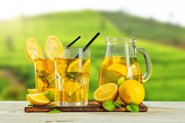 Cups of ice tea with plantation on background