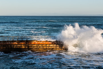 La Jolla Children's pool at high tide with crashing wave. 