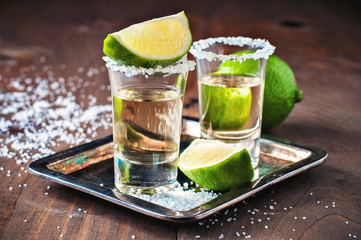 Tequila gold, Mexican, alcohol in shot glasses, lime and salt, toned image, selective focus