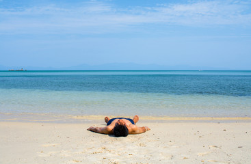 Fototapeta na wymiar Man with no shirt lay down on the beach