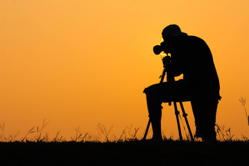 silhouette of photographer shooting photo for a sunrise