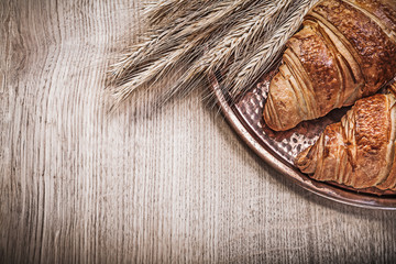 Composition of wheat rye ears buns copper tray on wooden board