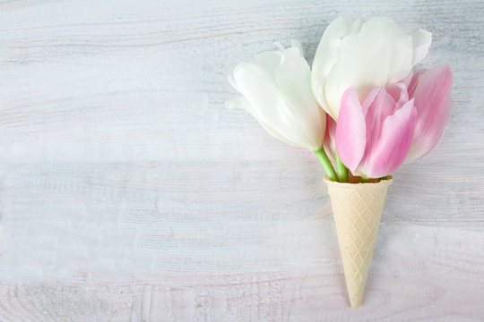 tulips pink and white in a waffle cone on a wooden background
