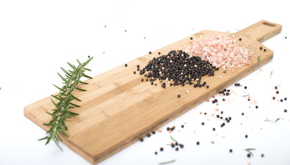 Peppercorns and Himalayan rock salt on a chopping board.