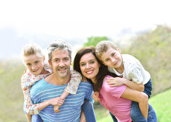 Parents giving piggyback ride to kids outside